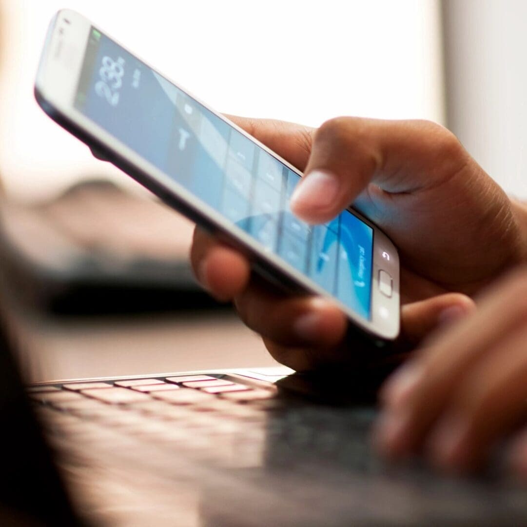 A person is using their cell phone while sitting at the keyboard.