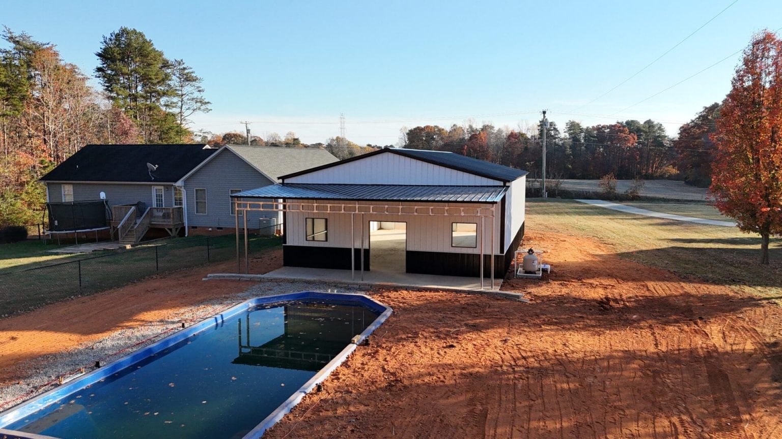 White metal building with pool in yard.